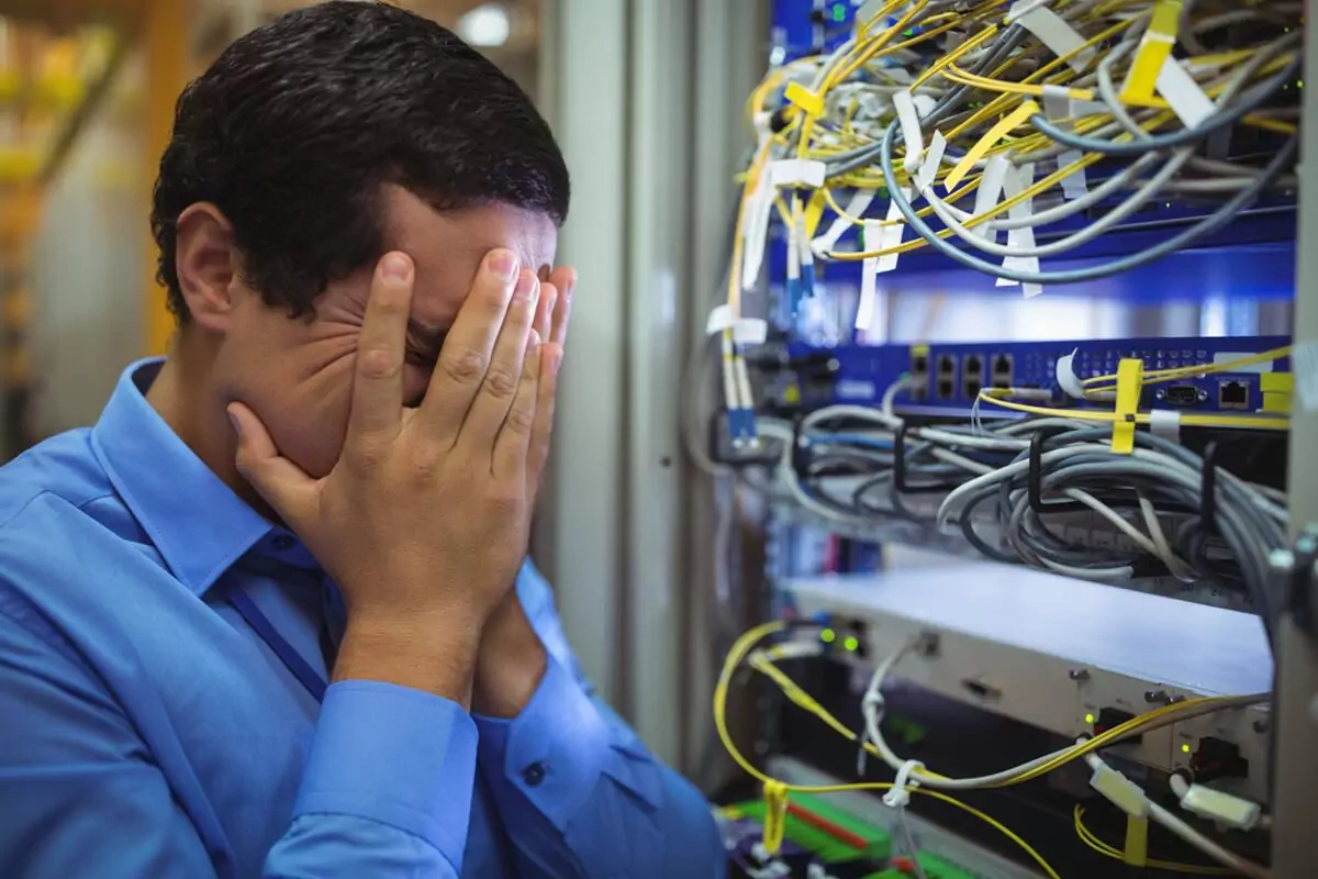Technician getting stressed over server maintenance in server room Technician getting stressed over server maintenance in server room